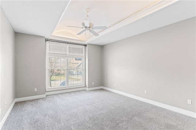 empty room with ceiling fan, carpet, baseboards, and a raised ceiling