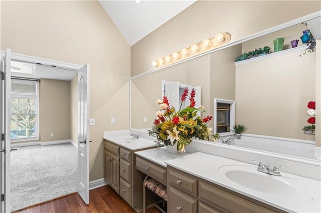 full bathroom featuring baseboards, lofted ceiling, wood finished floors, a garden tub, and vanity