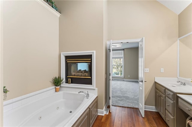 bathroom with baseboards, a tub with jets, wood finished floors, and vanity