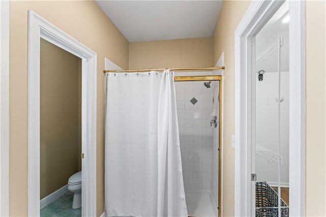 full bath with a stall shower, baseboards, toilet, and tile patterned floors