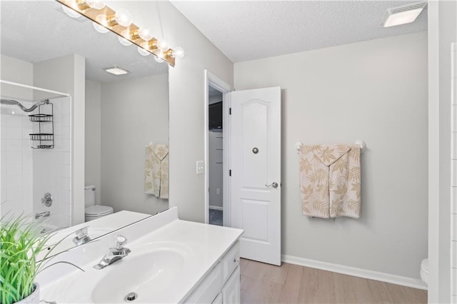 bathroom featuring toilet, a textured ceiling, baseboards, and wood finished floors