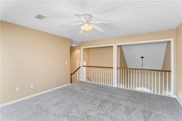 carpeted empty room with baseboards, visible vents, and a ceiling fan