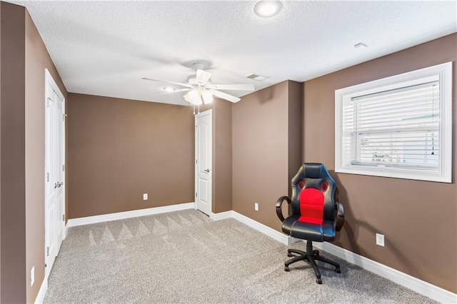 office featuring baseboards, visible vents, light colored carpet, ceiling fan, and a textured ceiling