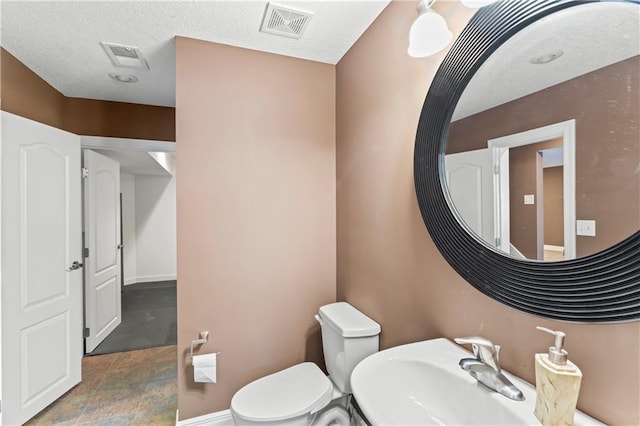 half bath with baseboards, visible vents, a sink, and toilet