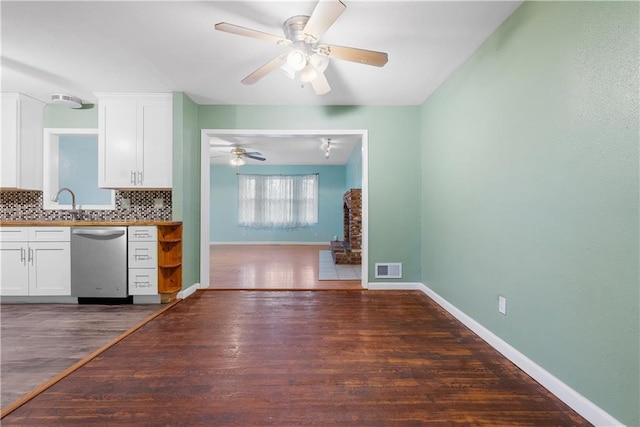 kitchen featuring backsplash, dark wood-type flooring, stainless steel dishwasher, ceiling fan, and white cabinetry