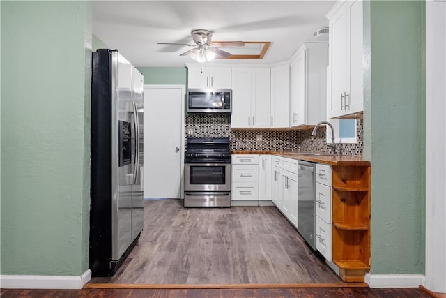 kitchen with backsplash, stainless steel appliances, sink, hardwood / wood-style flooring, and white cabinets