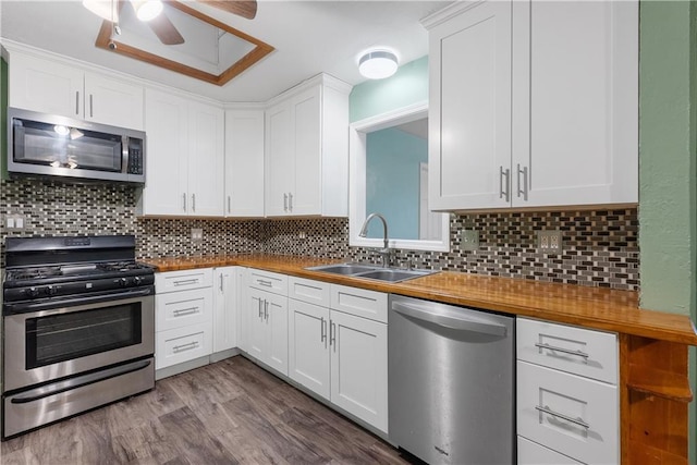 kitchen with wooden counters, white cabinets, sink, tasteful backsplash, and stainless steel appliances