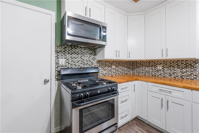 kitchen with wood counters, appliances with stainless steel finishes, white cabinets, and tasteful backsplash