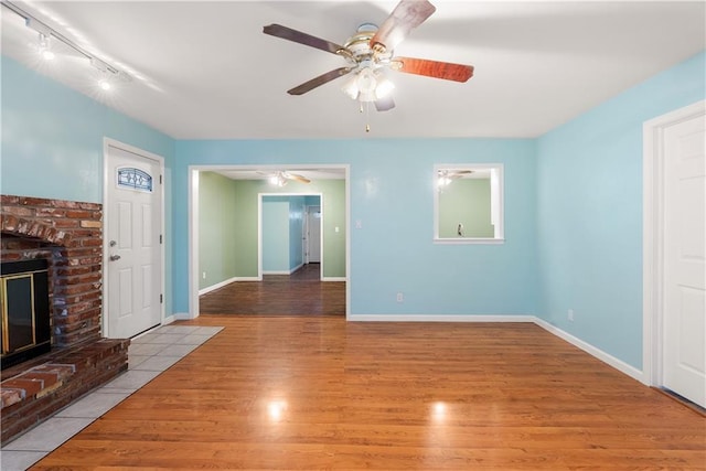 unfurnished living room with ceiling fan, light hardwood / wood-style flooring, and a brick fireplace