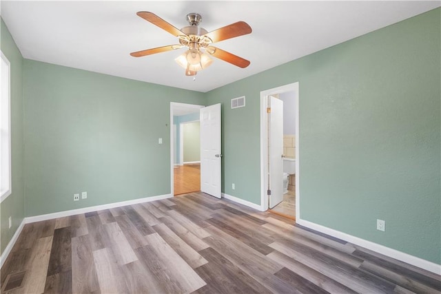 unfurnished bedroom with light wood-type flooring, ensuite bathroom, and ceiling fan