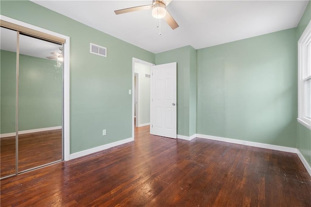 unfurnished bedroom with dark hardwood / wood-style flooring, a closet, and ceiling fan