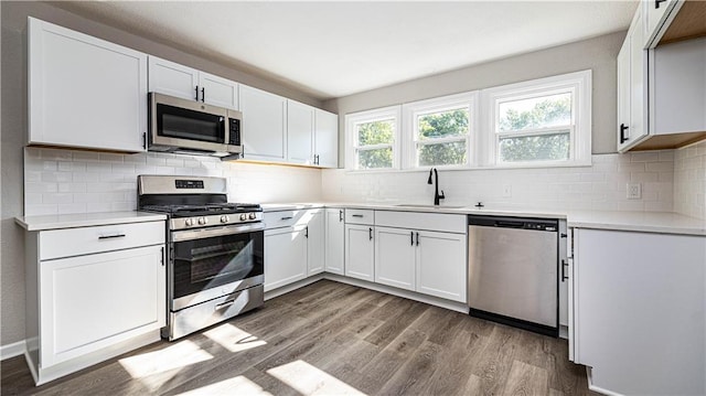 kitchen featuring tasteful backsplash, stainless steel appliances, sink, light hardwood / wood-style floors, and white cabinetry