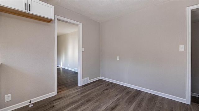 empty room featuring a textured ceiling and dark wood-type flooring