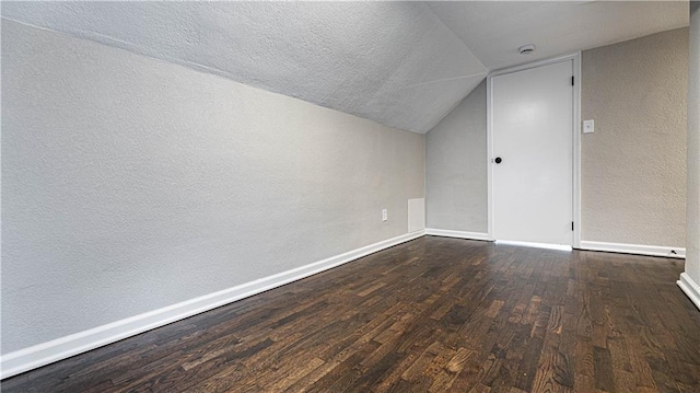 additional living space with dark hardwood / wood-style floors, a textured ceiling, and vaulted ceiling