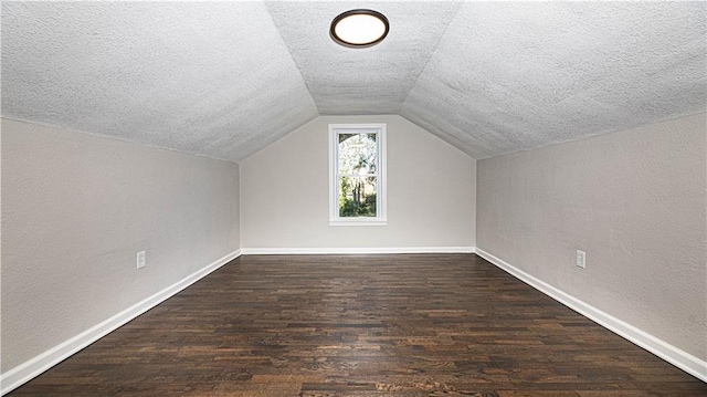 additional living space with a textured ceiling, dark hardwood / wood-style flooring, and vaulted ceiling