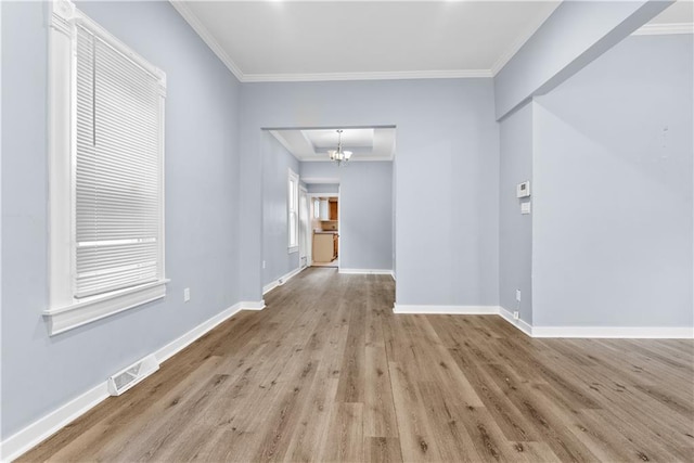 spare room with light wood-type flooring, an inviting chandelier, and ornamental molding