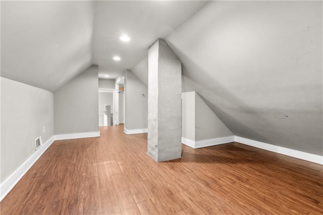 additional living space featuring light wood-type flooring and vaulted ceiling