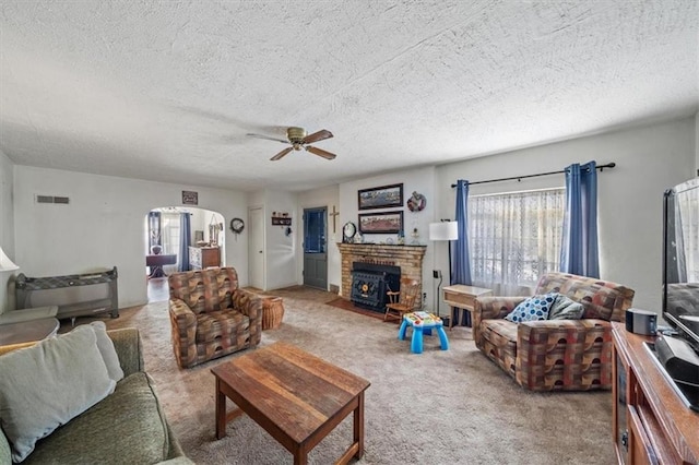 carpeted living room with a fireplace, a textured ceiling, and ceiling fan