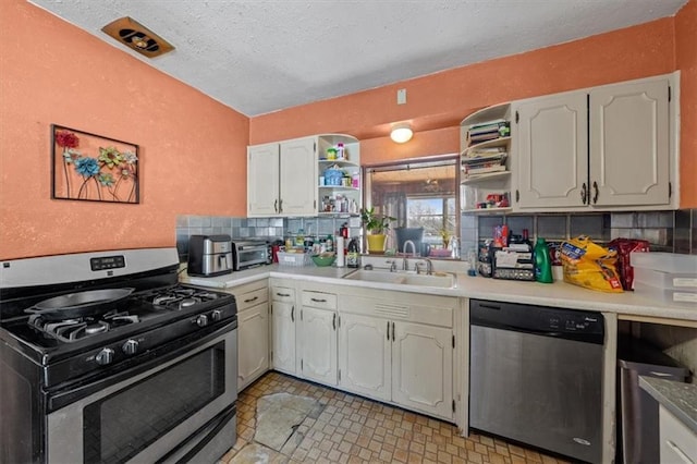 kitchen featuring sink, stainless steel appliances, backsplash, a textured ceiling, and white cabinets