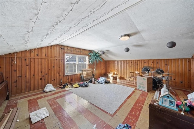 bonus room with a textured ceiling, wood walls, and vaulted ceiling