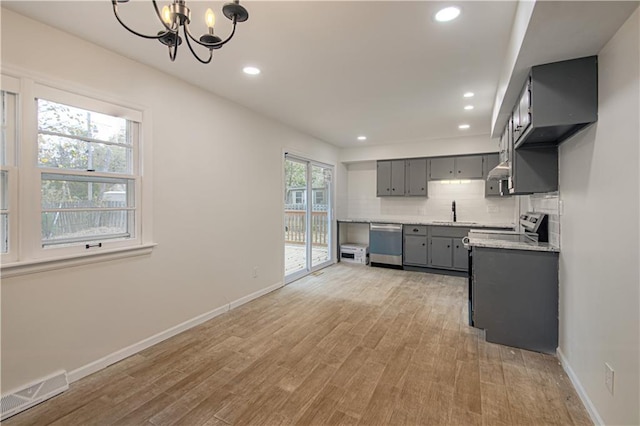 kitchen with backsplash, stainless steel appliances, an inviting chandelier, light hardwood / wood-style flooring, and gray cabinets