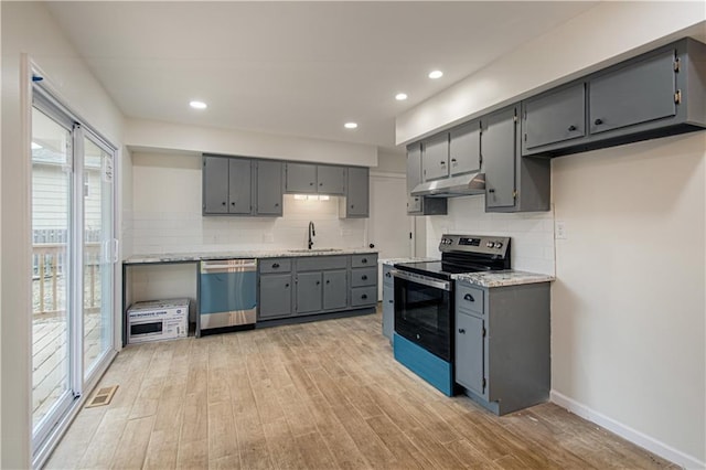 kitchen with light stone counters, light hardwood / wood-style floors, stainless steel appliances, sink, and gray cabinets