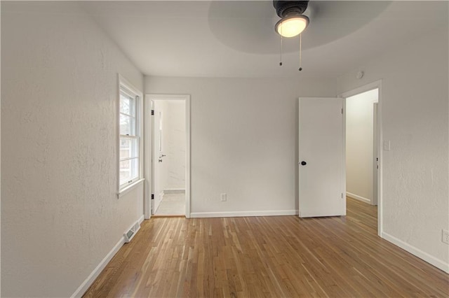 unfurnished bedroom with ceiling fan, hardwood / wood-style floors, and ensuite bathroom