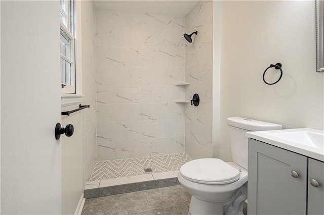 bathroom featuring vanity, toilet, and a tile shower