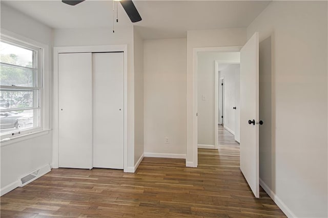 unfurnished bedroom with a closet, dark hardwood / wood-style floors, and ceiling fan