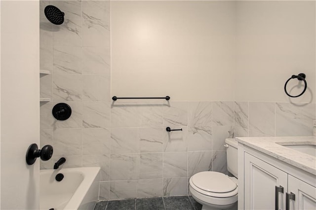 full bathroom featuring vanity, tiled shower / bath, tile patterned flooring, toilet, and tile walls