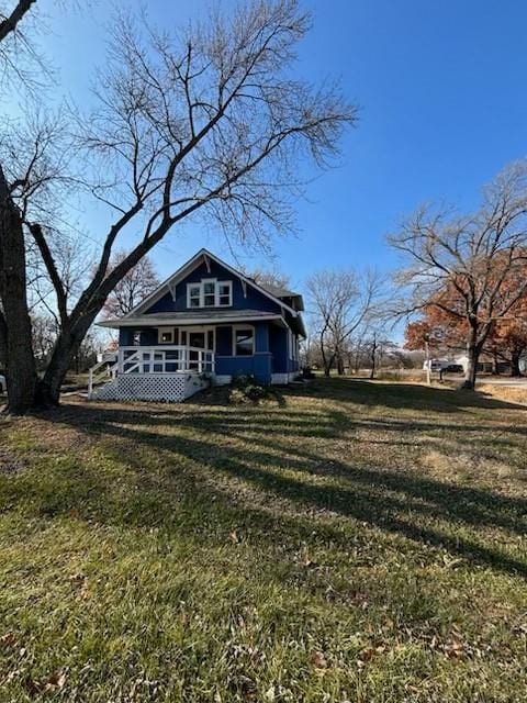 rear view of house featuring a lawn and covered porch