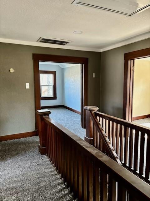 hallway featuring carpet, ornamental molding, and a textured ceiling