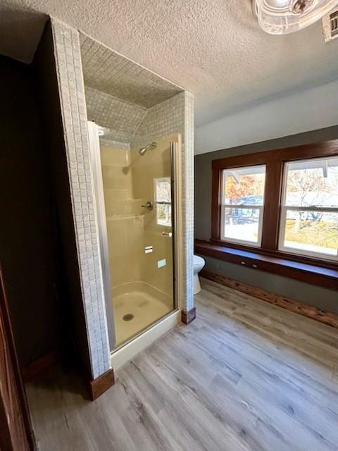 bathroom featuring walk in shower, hardwood / wood-style floors, a textured ceiling, toilet, and vaulted ceiling