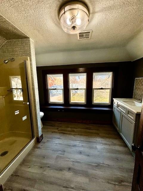 interior space with hardwood / wood-style floors, vanity, an enclosed shower, and toilet