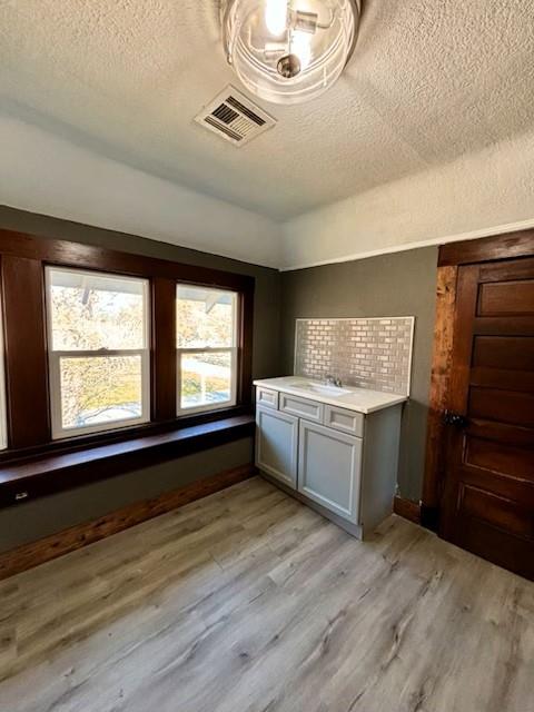 washroom featuring sink, a textured ceiling, and light wood-type flooring