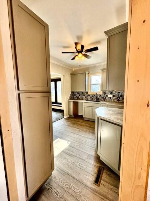 kitchen with ceiling fan, sink, light hardwood / wood-style flooring, decorative backsplash, and ornamental molding