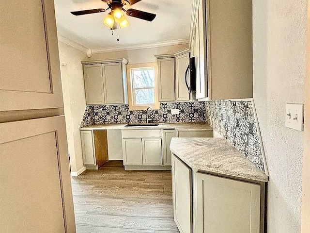 kitchen with crown molding, sink, ceiling fan, tasteful backsplash, and light hardwood / wood-style floors