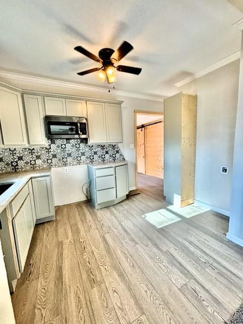 kitchen with tasteful backsplash, a barn door, ornamental molding, and light wood-type flooring