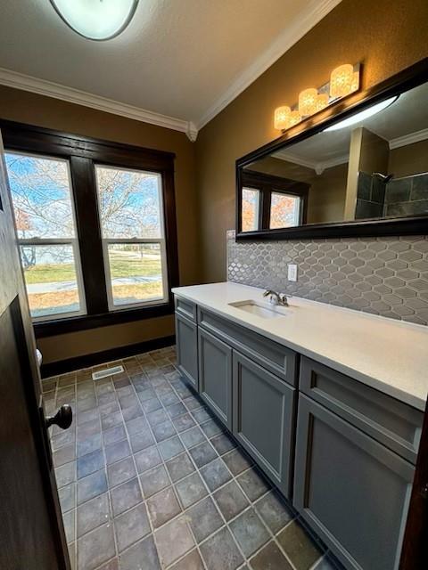 bathroom with decorative backsplash, vanity, a wealth of natural light, and ornamental molding