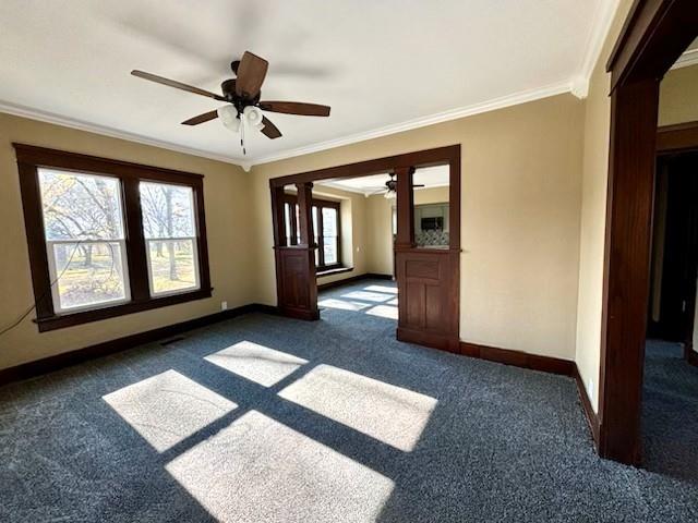 unfurnished room featuring dark colored carpet, a wealth of natural light, and ornamental molding