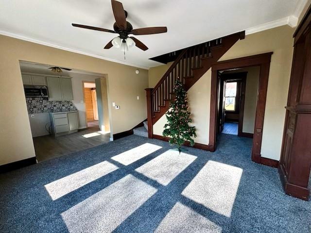 interior space featuring ceiling fan, dark carpet, and ornamental molding