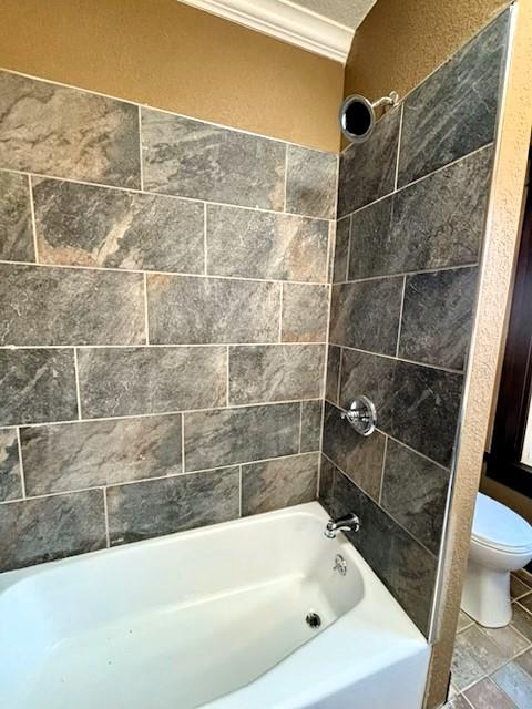 bathroom featuring tile patterned flooring, toilet, tiled shower / bath, and ornamental molding