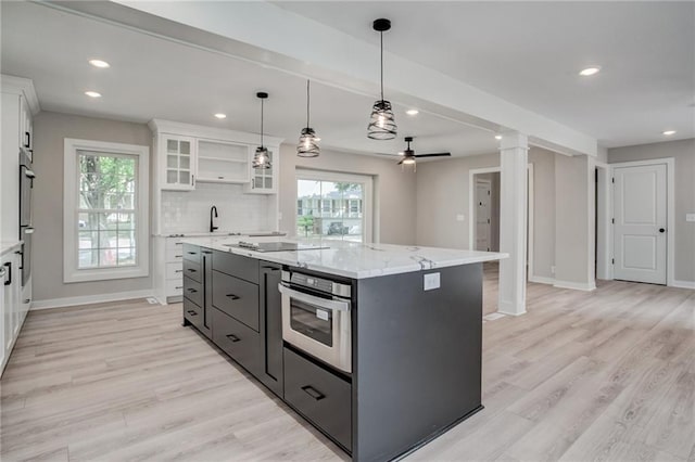 kitchen with tasteful backsplash, ceiling fan, a center island, and white cabinets