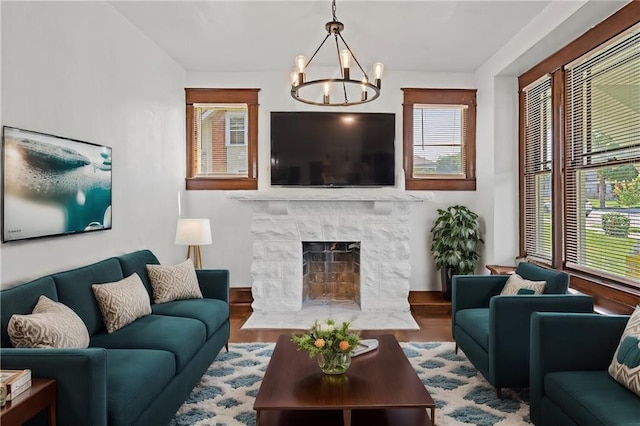 living room with a notable chandelier, wood-type flooring, and a tile fireplace