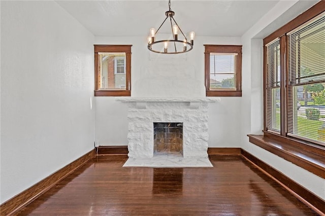 unfurnished living room with dark hardwood / wood-style floors, a fireplace, and an inviting chandelier