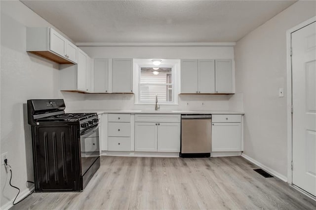 kitchen featuring gas stove, white cabinetry, stainless steel dishwasher, and sink