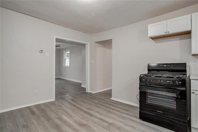 kitchen with light hardwood / wood-style floors, white cabinetry, and black range with gas cooktop