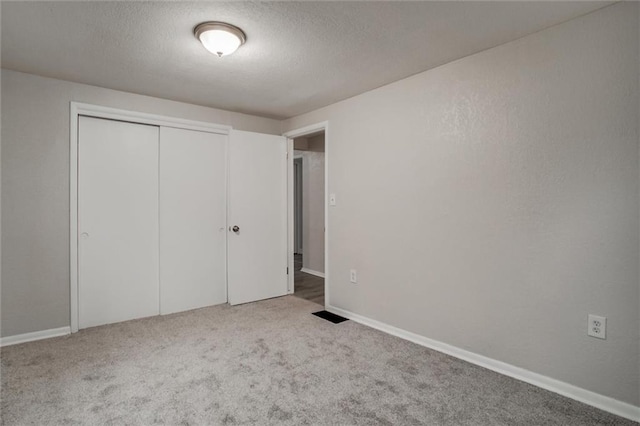 unfurnished bedroom featuring light carpet and a closet