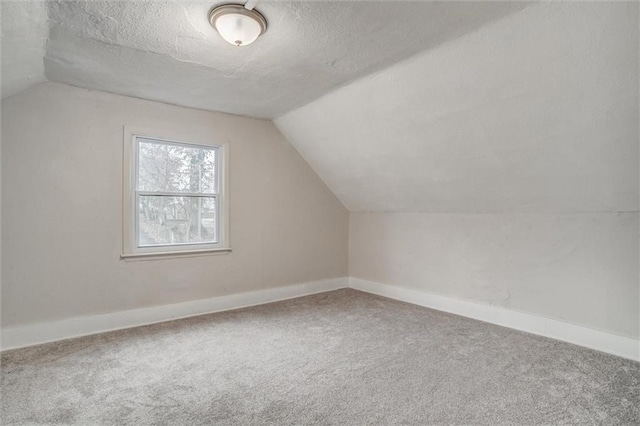 additional living space featuring carpet flooring, lofted ceiling, and a textured ceiling