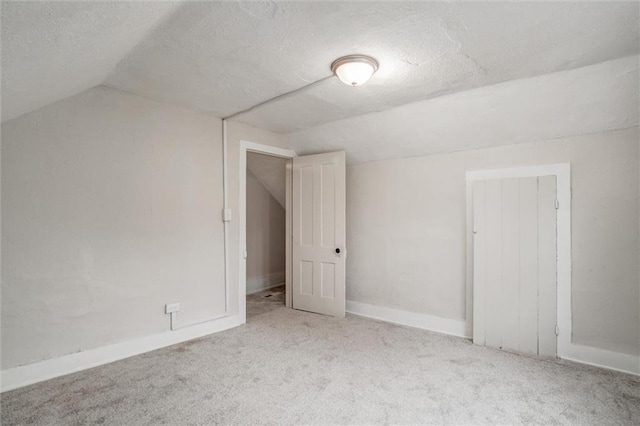 bonus room with light carpet, a textured ceiling, and vaulted ceiling